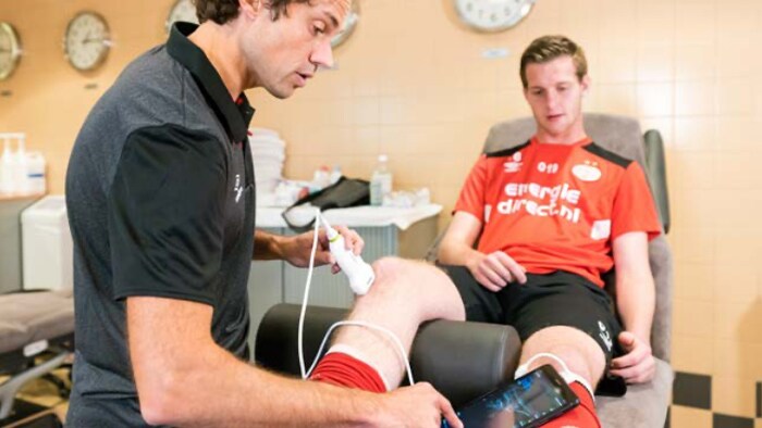 Professionnel de la santé utilisant un échographe portable sur le genou d’un athlète