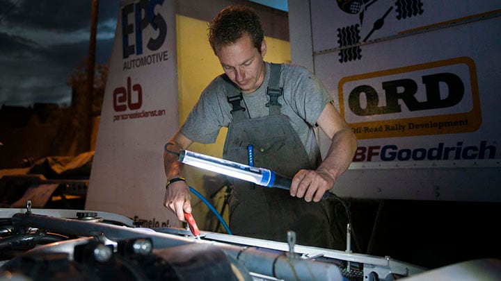 An LED work lamp helps a man to see more clearly while he is fixing a car